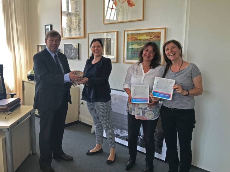 Ein Mann und drei Frauen mit einem Scheck. 